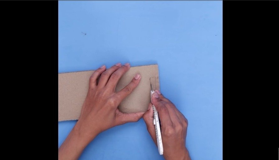 cutting two holes on the cardboard